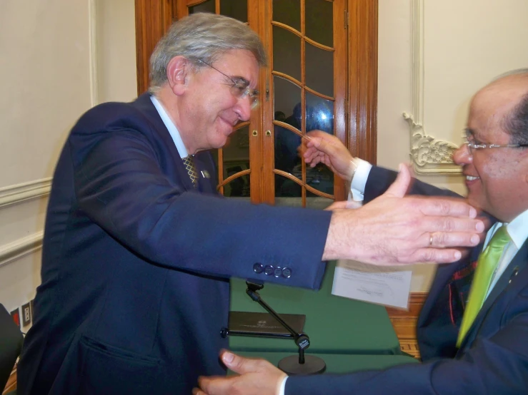 two men standing close to each other at a desk