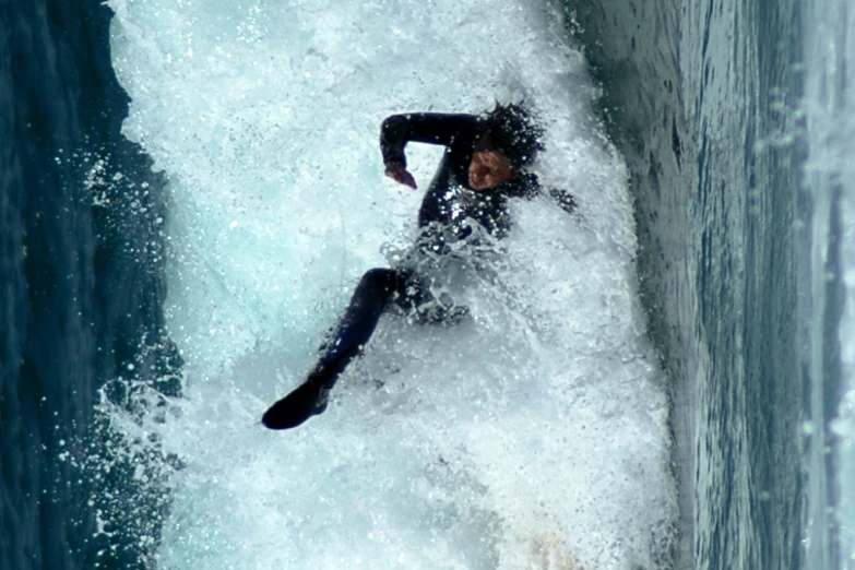 a surfer in a black wetsuit riding a wave