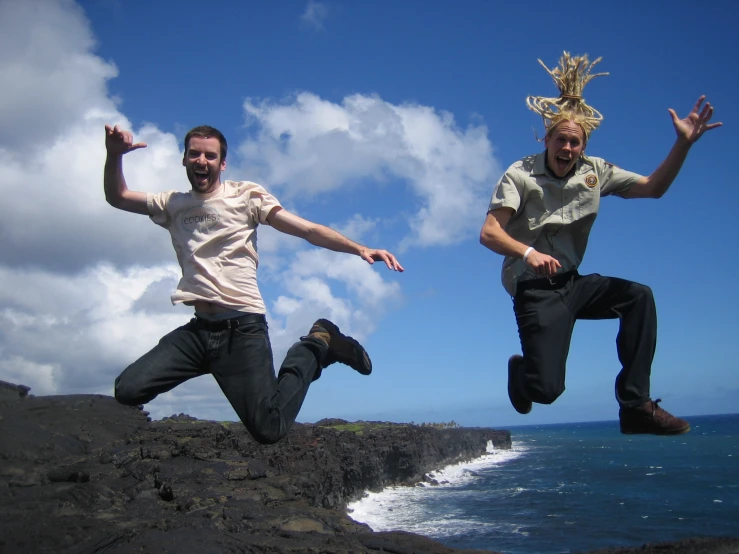 two men jumping from the shore near the ocean