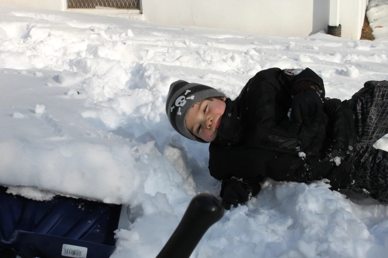 a person lying in the snow with a hat on