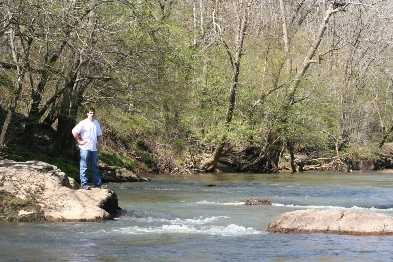 a man standing on a rock in the middle of a river