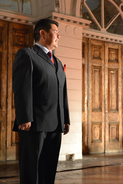 the man is wearing a suit and standing in a large room