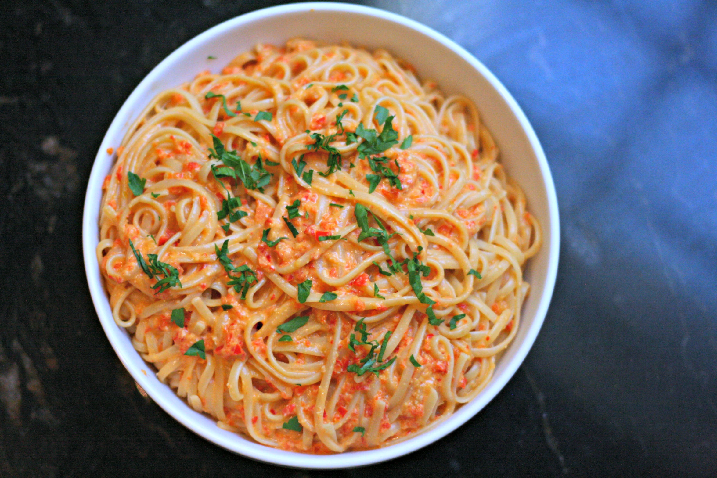 a white bowl filled with spaghetti, red sauce and parsley