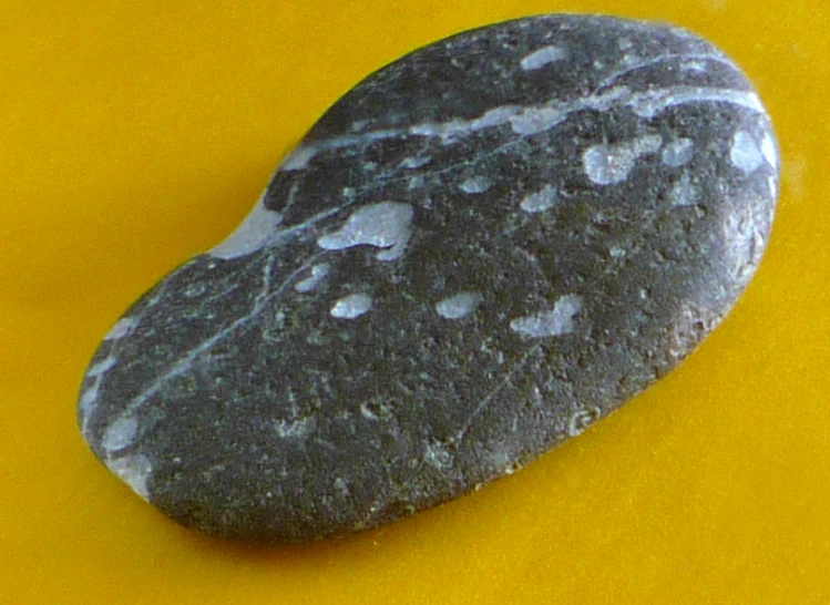 large rock placed on yellow surface with water droplets