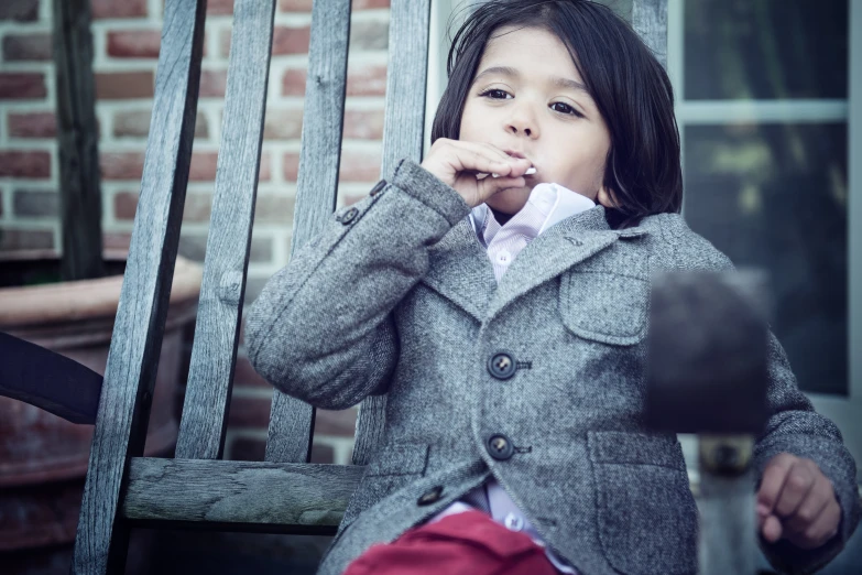 the little girl is eating on the outside chair