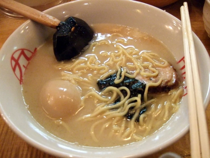 chopsticks rest on a bowl of ramen soup with a fried egg