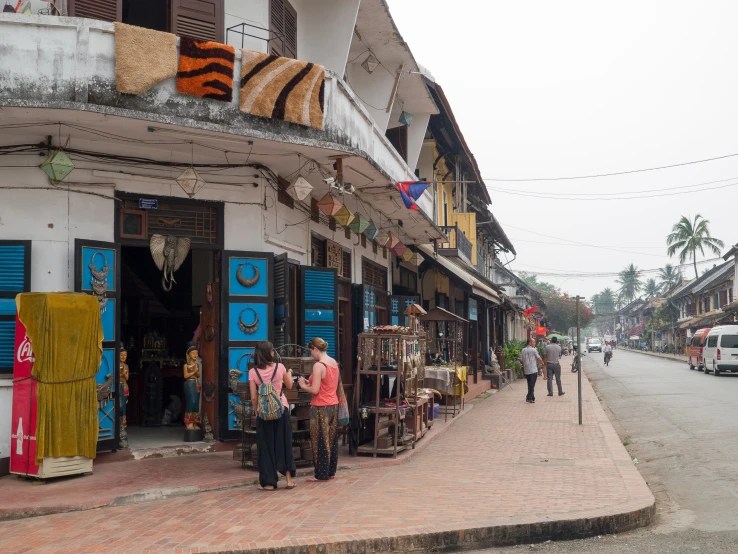 there are people walking down the street and a store is on the corner