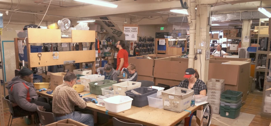 a group of people sitting at a table with boxes