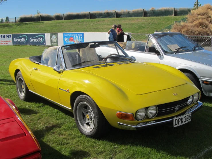 a yellow car and two other cars on display