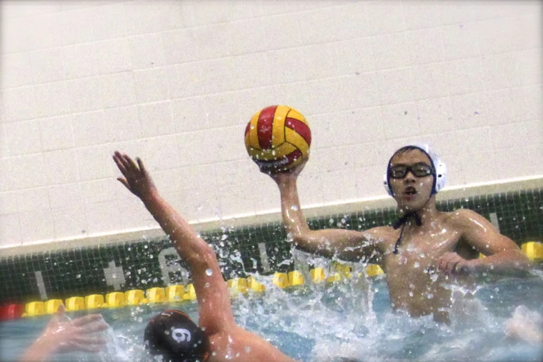 two people in a swimming pool playing with a ball