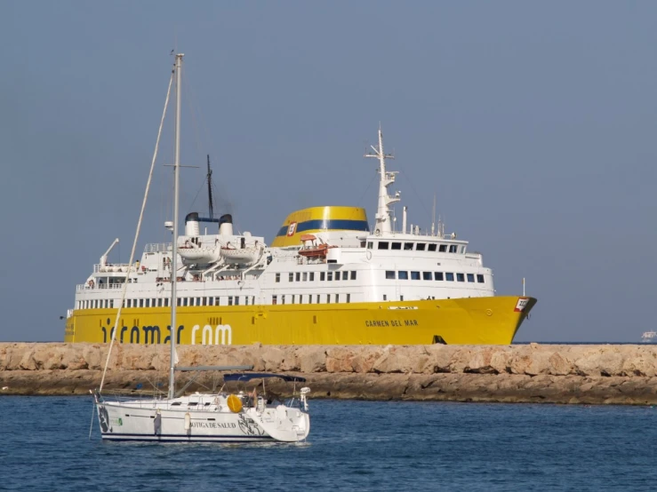 a large yellow and white ship in the water near the shore