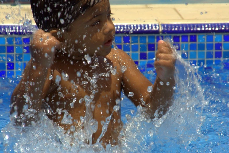 a  in the water with his hands in his hair and his face is covered by splashing water