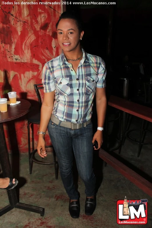 a woman in plaid shirt standing next to table with a cup of drinks