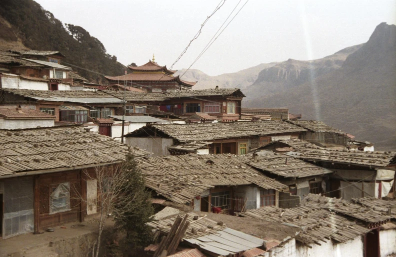 a row of houses on a hillside, with mountains in the background