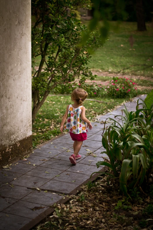 a small child wearing pink shoes and walking away from a house