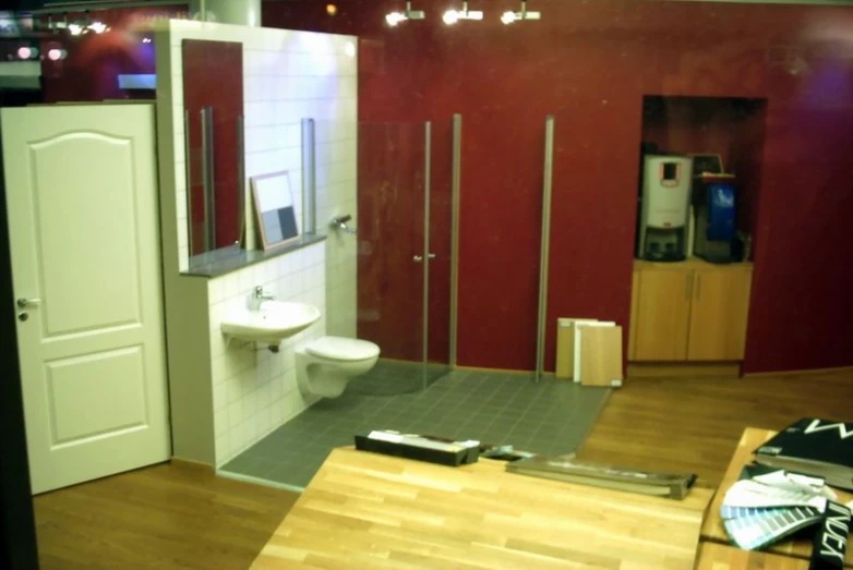 the interior of a modern bathroom with red walls and white appliances