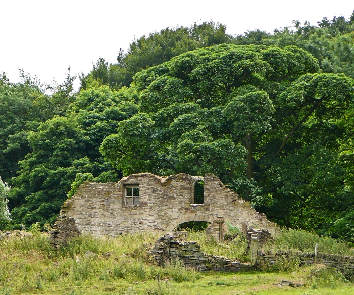 an old building sitting in a field surrounded by trees