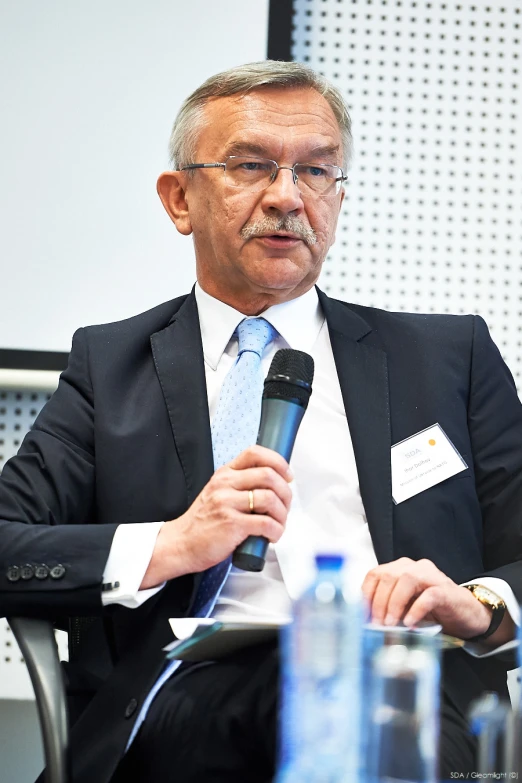 a man in a suit is sitting in a chair talking