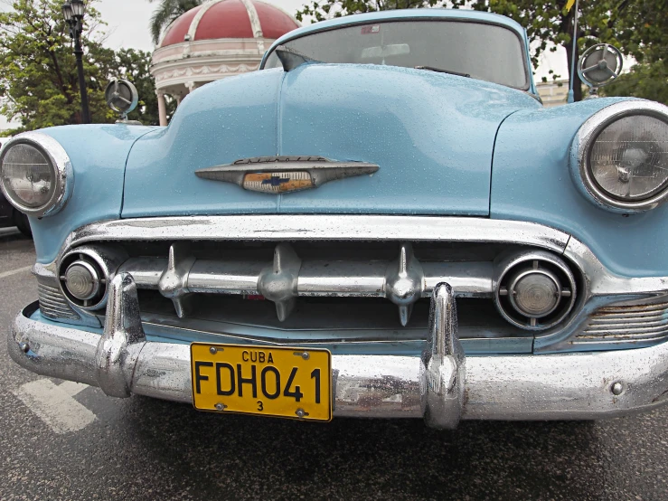 a blue classic car parked at a bus stop