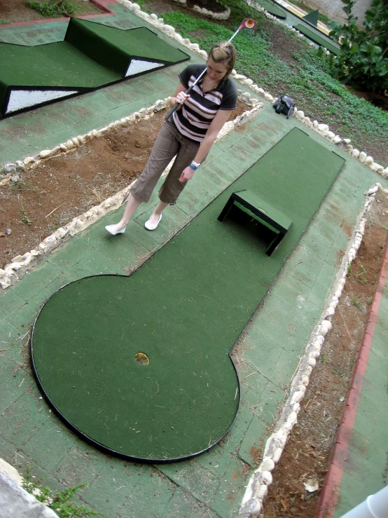 a woman is putting golf balls at a mini golf course
