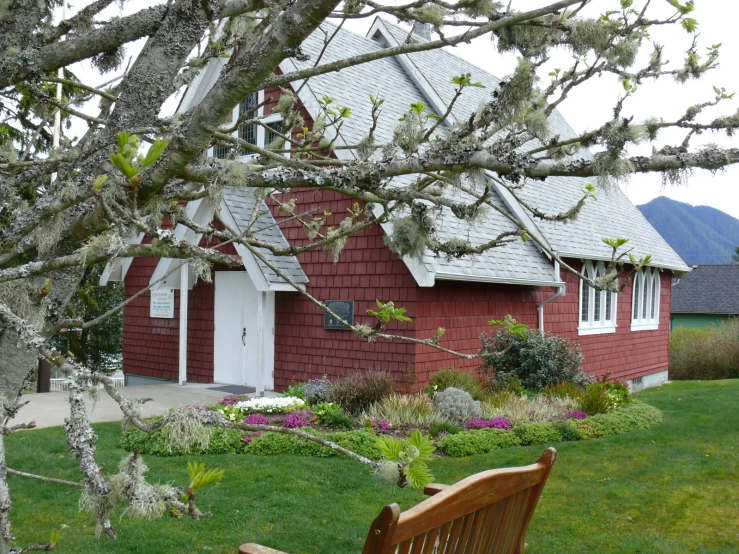 a wooden bench is sitting outside the red house