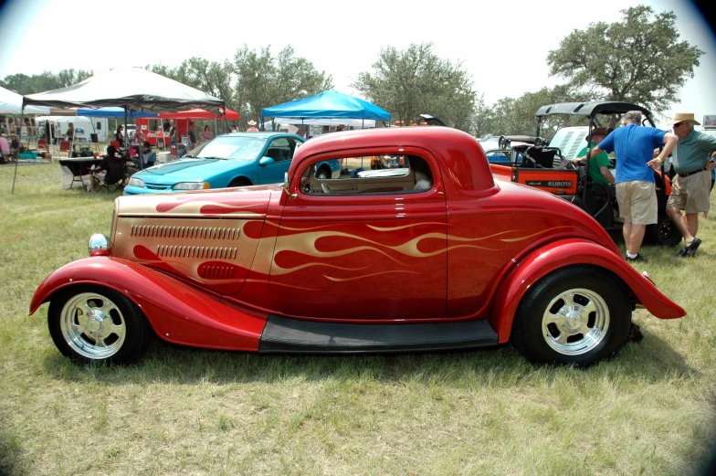 vintage red and gold car on display in a field