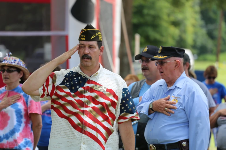 a man with an american flag shirt salutes his hand at a fourth of july parade