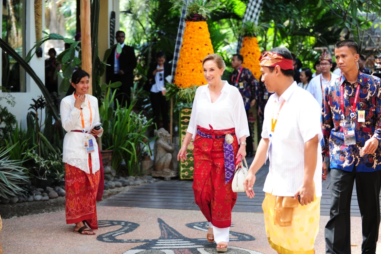 two women walking down a pathway with other people standing around