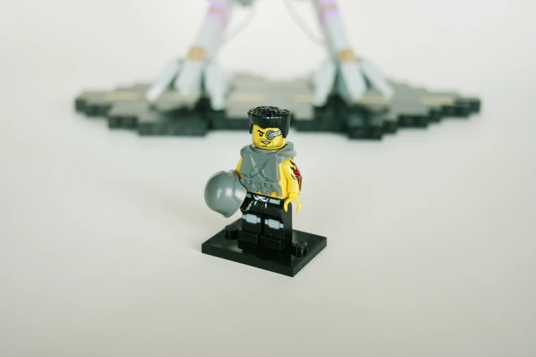 lego figurine holding metal ball with legs bent up