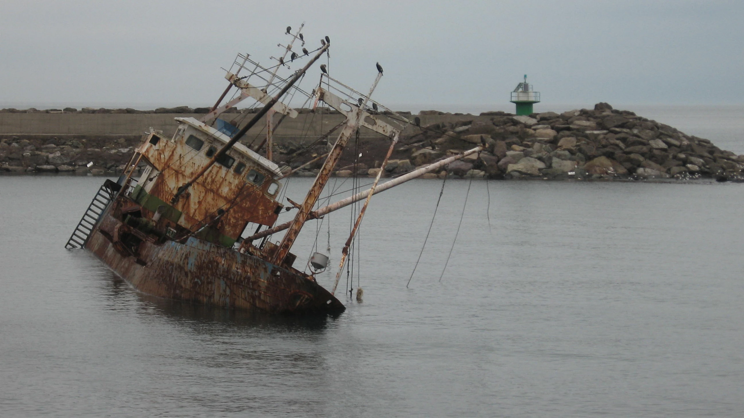 a ship is sitting in the water off a shore