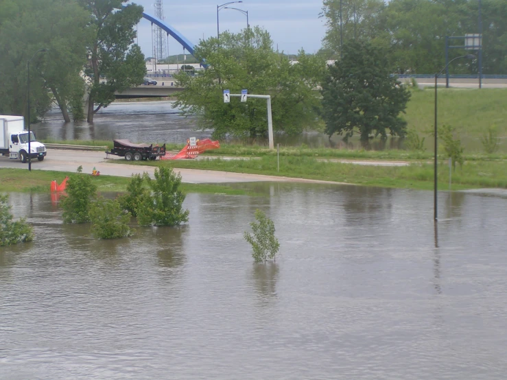 a street flooded with water next to trees and street signs