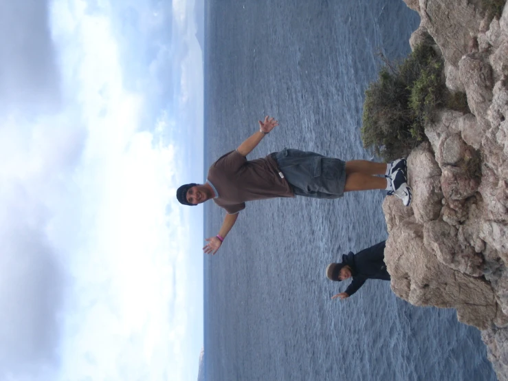 a man stands on the rocks waving to soing