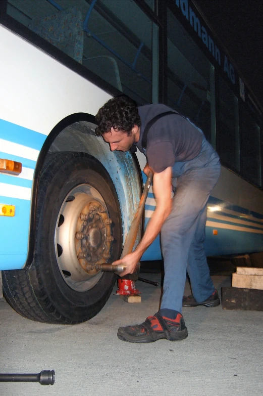 a man working with wood between the tire and his bus