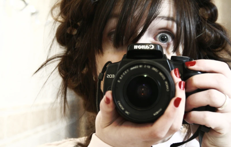 a woman holding a camera in front of her face