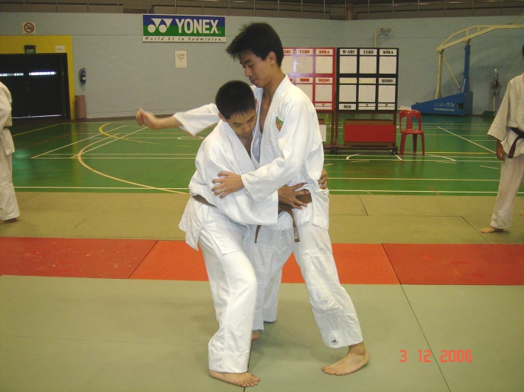 two people engaged in martial training inside of a gymnasium