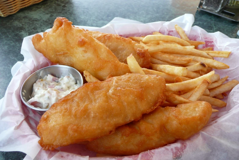 a basket filled with fish and fries on top of a table