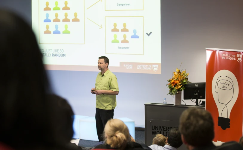 the man stands near a projector in front of people