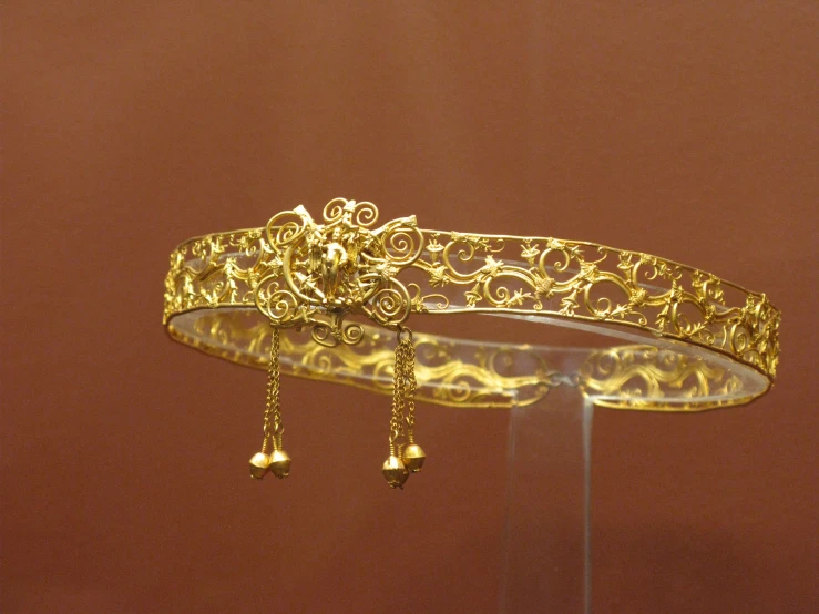 an intricate gold celet that has bells and pearls