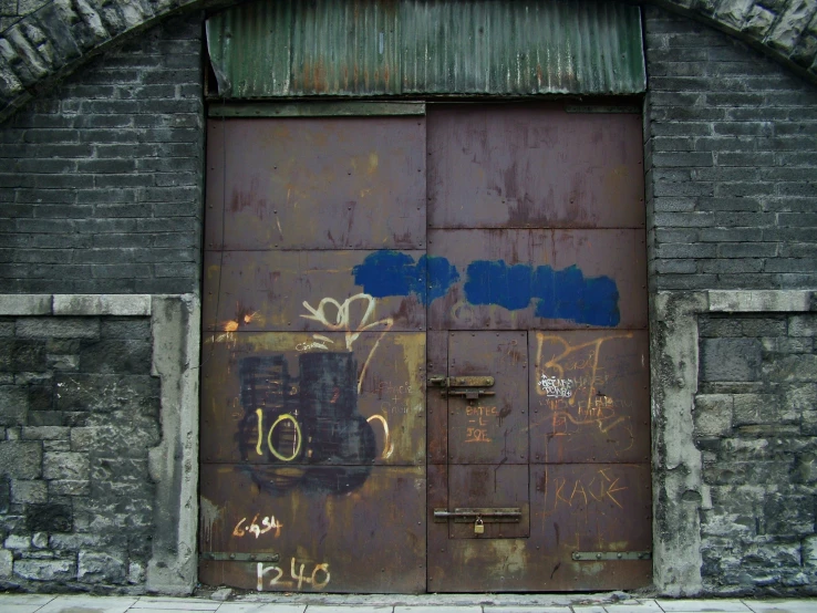 a very old, rusty, wooden door with graffiti