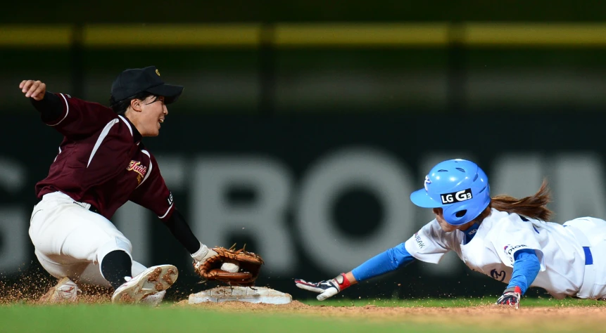 a runner sliding to first base with the catcher near him