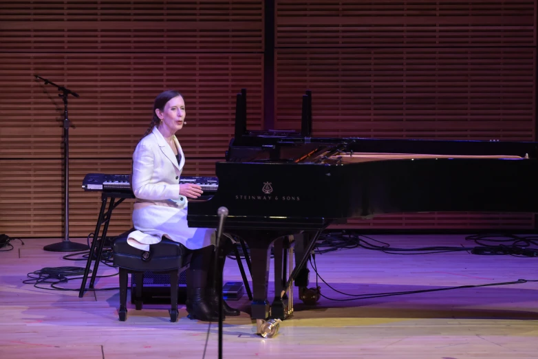 a woman sitting at a piano on stage