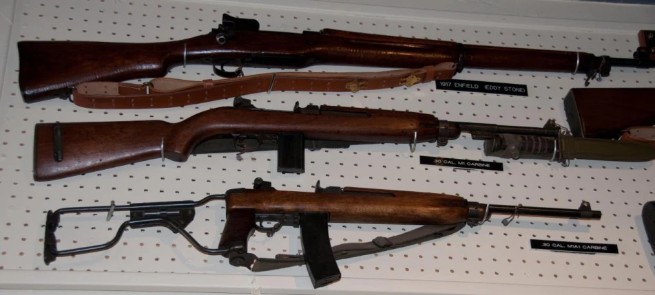 several guns and rifles on a pegboard with labels and other items