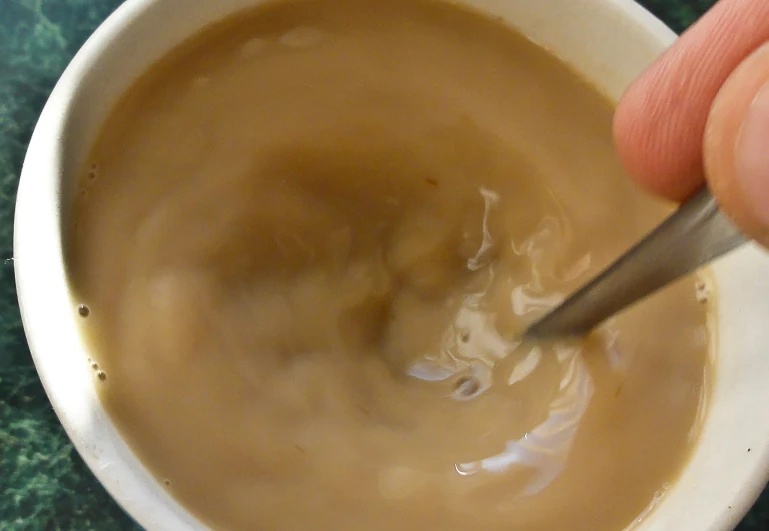 a person spooning into some brown soup