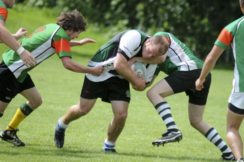 rugby players are playing in the field, with green grass