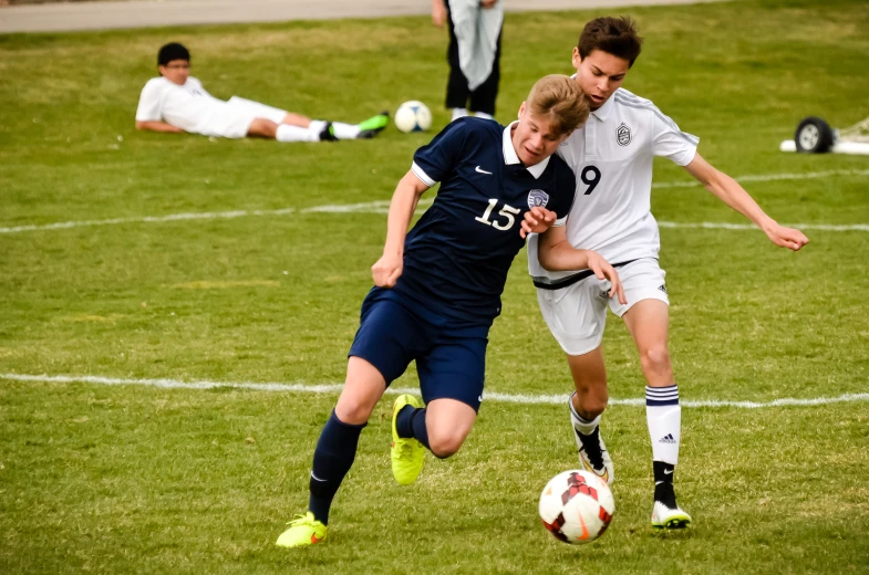 two men on opposite teams playing soccer on a green field