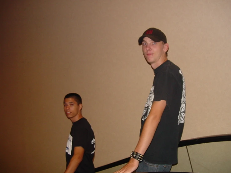 two guys standing in front of a wall holding a remote