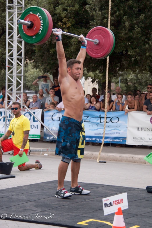 a man is lifting two weight bars while people watch