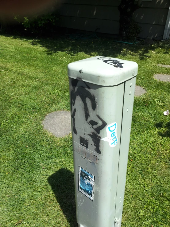 a white trashcan covered in graffiti next to a house