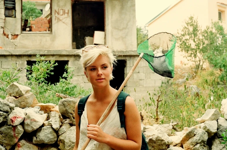 the woman is standing near a house with a backpack on