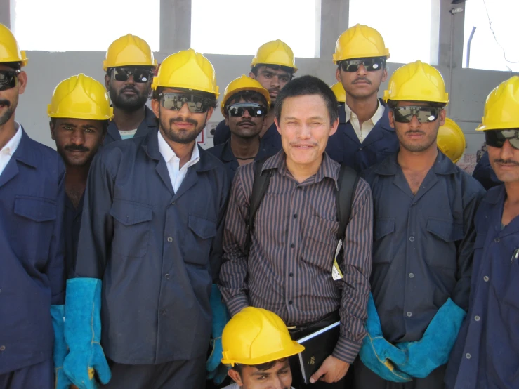 a man stands amongst many men in hard hats